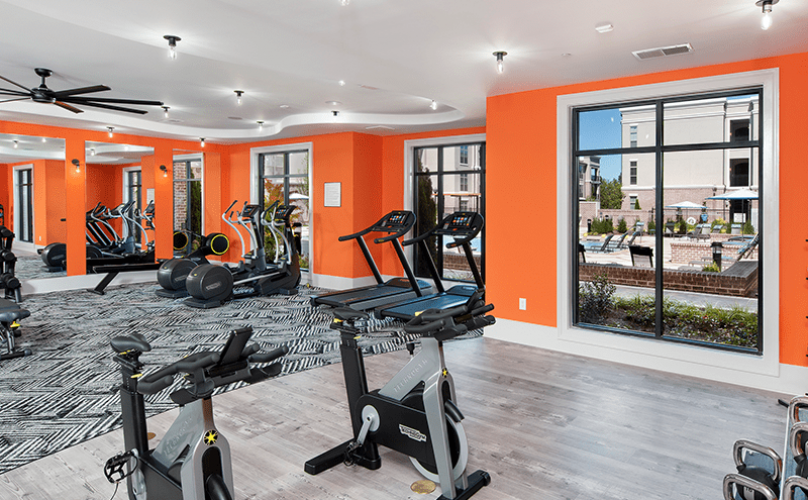 fitness center with equipment, plenty of spacious areas, accent-colored walls & bright lighting from multiple windows